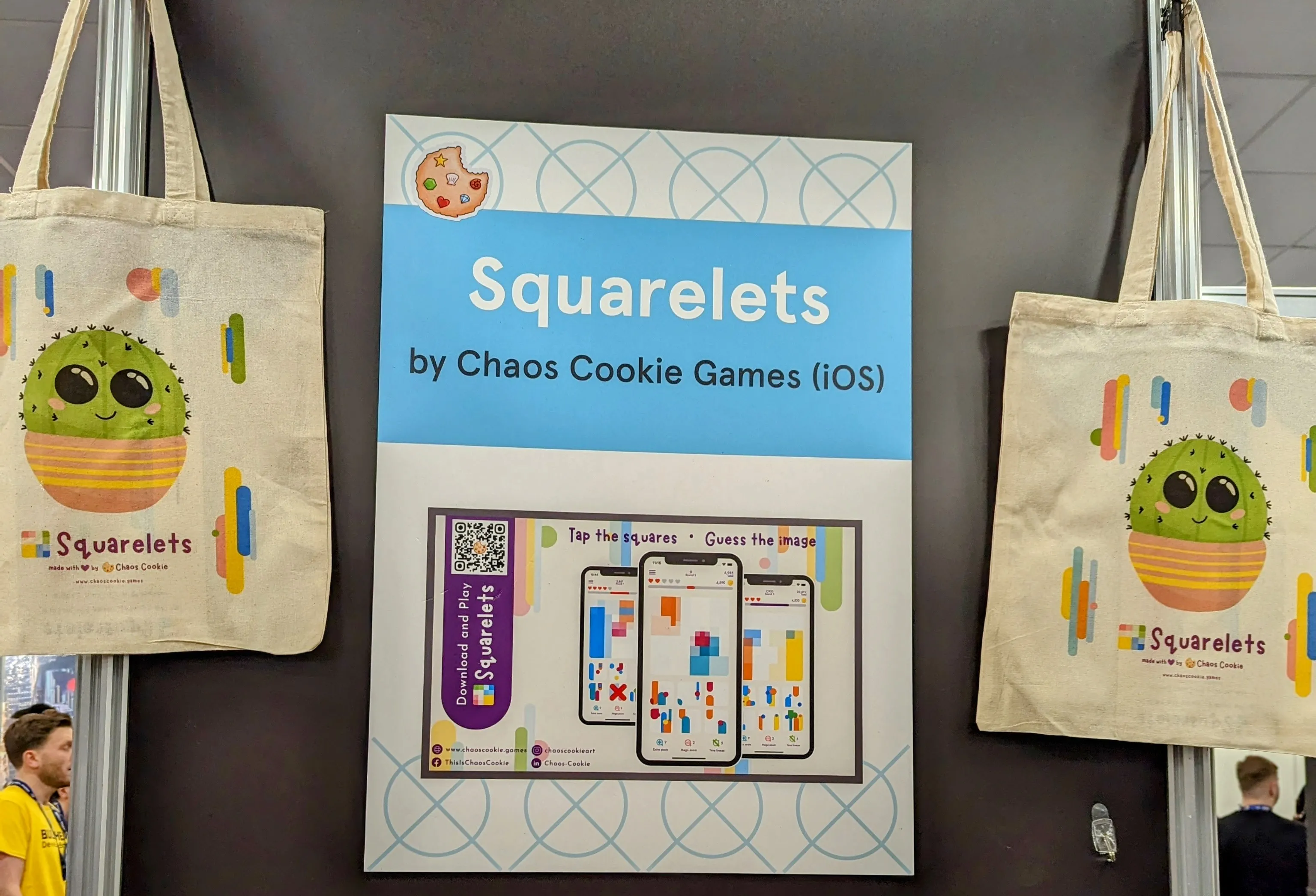 A banner from the recent Develop: Brighton conference showing Squarelets. There are two tote bags with Squarelets mascot cactus called Pin on both sides of the banner.